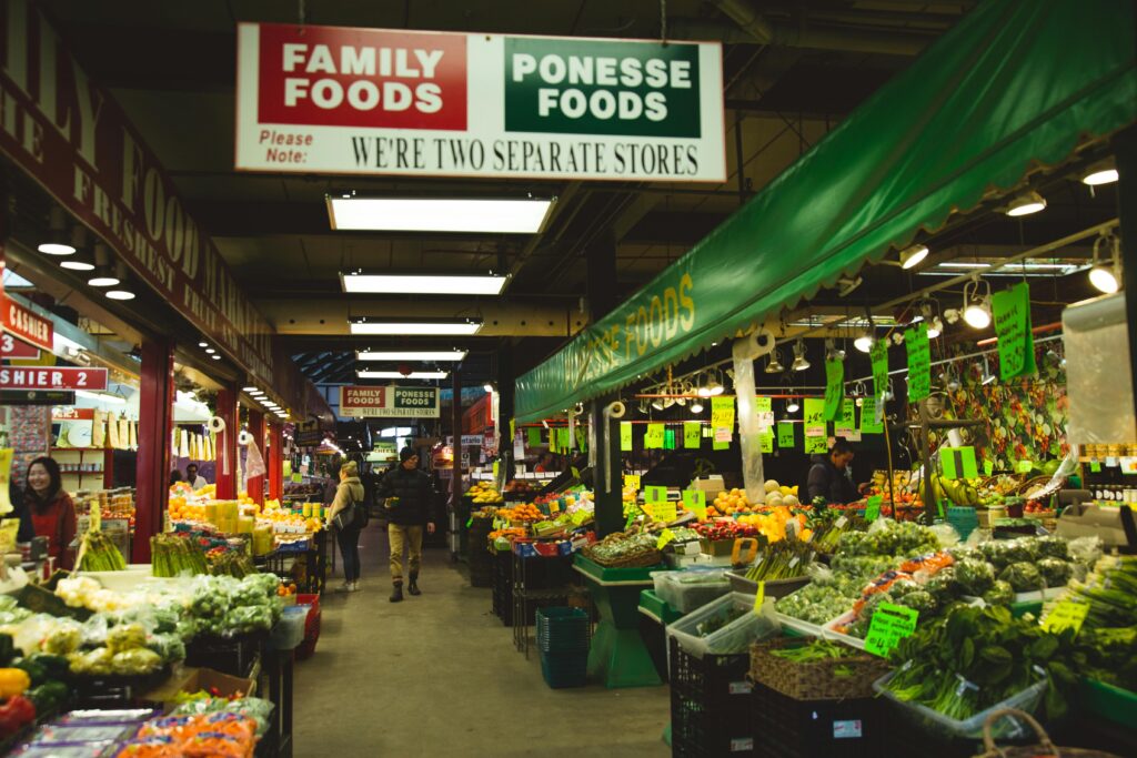 Indoor market scene with various fresh produce and customers in Toronto, Canada.